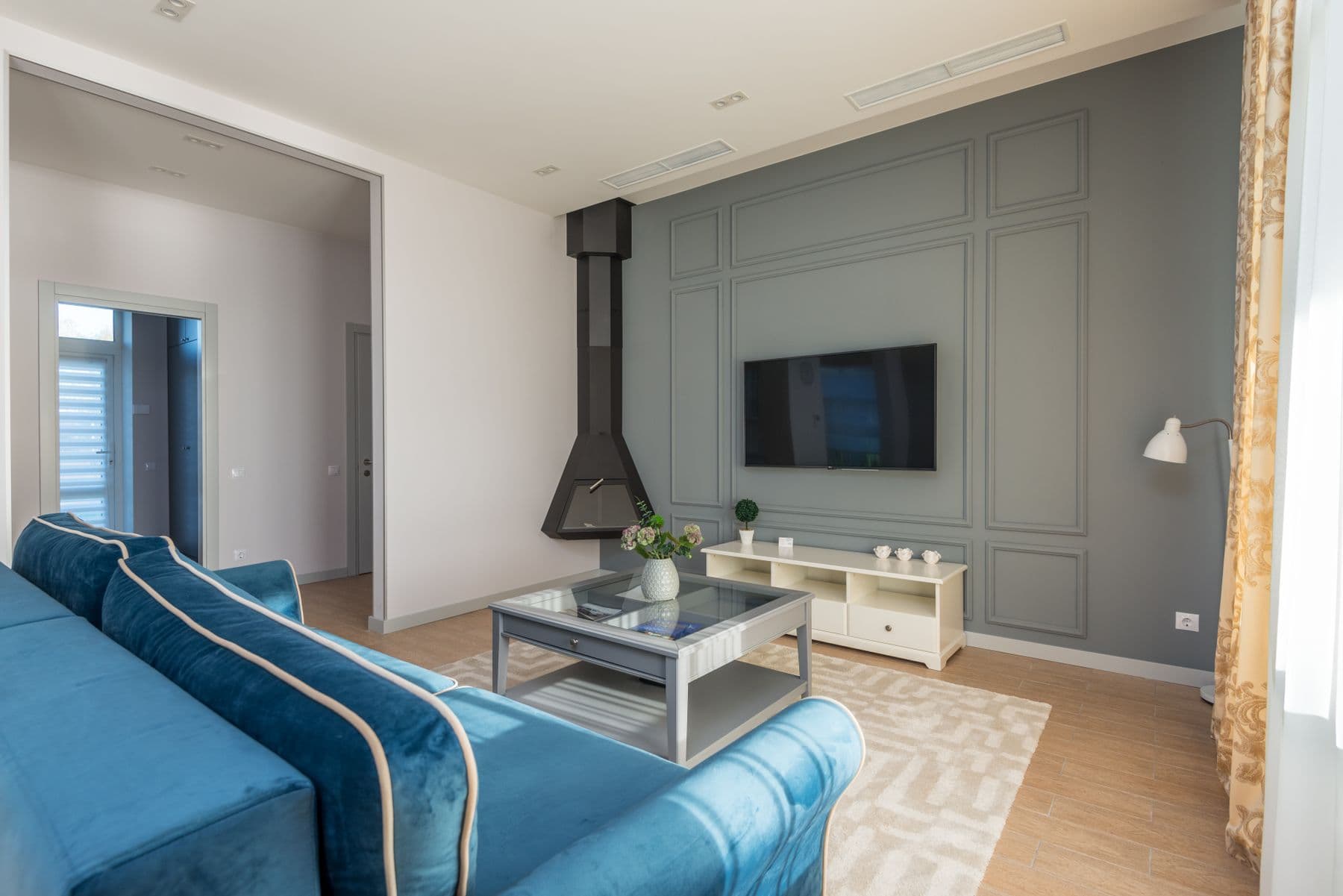 Flat-screen TV mounted on a grey paneled feature wall beside a black suspended fireplace