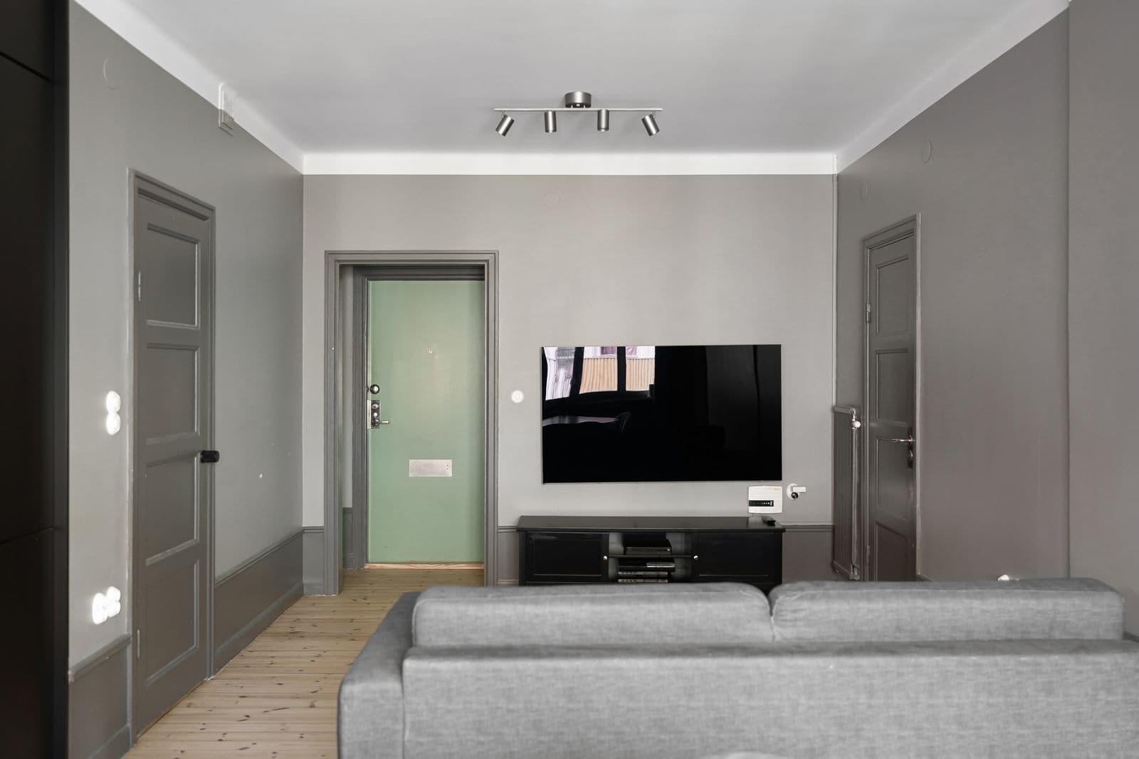 Grey living room with a TV mounted on the wall above a low black media console