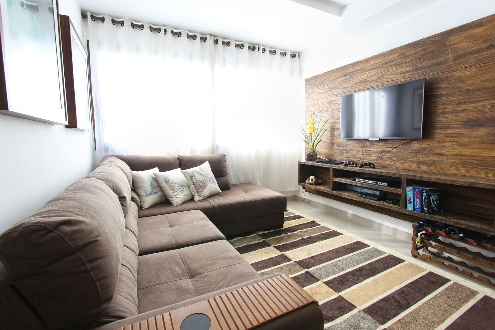Brown sectional sofa facing a wall-mounted TV in a warm, sunlit living room