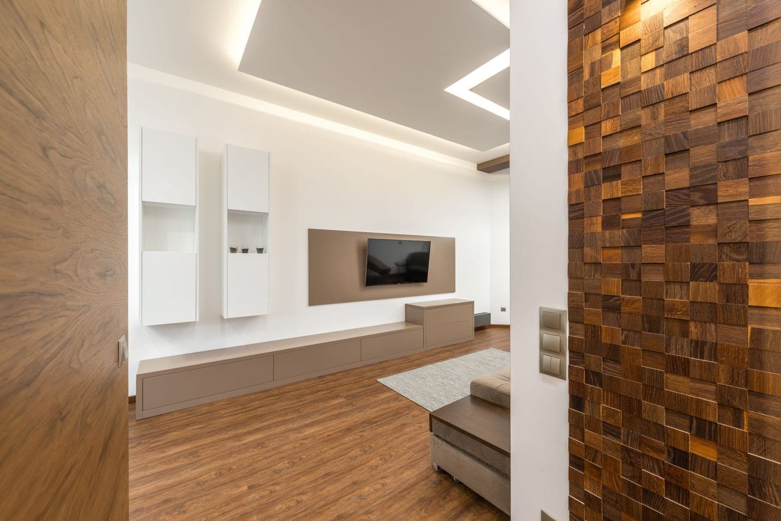 TV on a taupe media panel beside a wall of stacked wood blocks